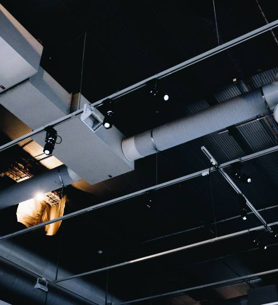 Low angle shot of a metal black ceiling with white ventilation pipes A low angle shot of a metal black ceiling with white ventilation pipes